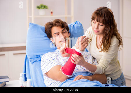 Liebevolle Frau auf der Suche nach verletzten Mann im Krankenhaus Stockfoto