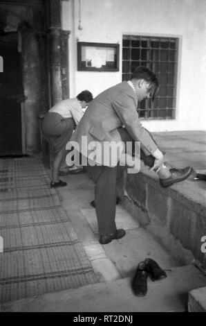 Spanien, Griechenland - Ein Mann und eine Frau ziehen sich nach dem 206 einer Kirche sterben Schuhe wieder ein, Delos, Panorama, 1950er Jahre. Ein Mann und eine Frau, die ihre Schuhe nach dem Besuch einer Kirche auf der Insel Delos, Griechenland, 1950. Stockfoto