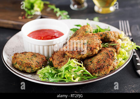 Hausgemachte Kuchen Kabeljau Fisch, Spinat und Paniermehl. Auf Platte mit Sauce serviert. Die Koteletts aus Hackfleisch/Cod. Leckeres und nahrhaftes Mittagessen oder Abendessen. Stockfoto