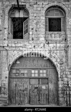 Altes Lagerhaus mit gewölbten Tür und Fenster, Schwarz und Weiß Stockfoto