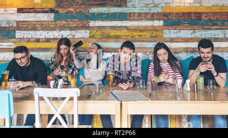 Gruppe von Jugendlichen an den trendy Pub in sozialen Medien süchtig Stockfoto