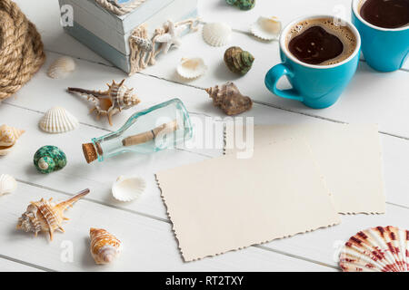 Nautische life style Artikel: Flasche mit Nachricht, Muscheln, Brust. Kaffeetassen und Alte, leere Foto auf der Innenseite. Retro getönt. Stockfoto