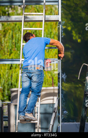Young man fixing a construction element using electrical screwdriver. Renovation, construction, do it yourself concept. Stockfoto