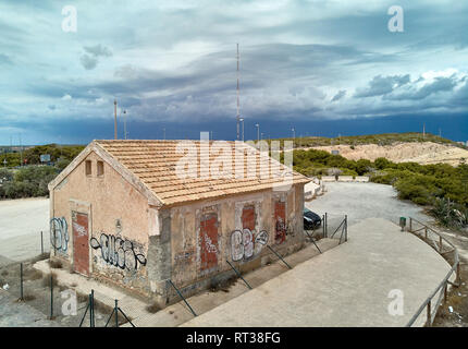 Torrevieja, Spain-August 16, 2018: Landschaft und Parkplatz für Autos überholt altes Gebäude mit Graffiti an den Wänden Moody bewölkten Himmel. Alicante provi Stockfoto