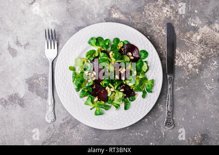 Vegetarische Salat von frischen, rohen Gemüse Salat rote Rüben auf eine weiße, runde Platte auf einem grauen Hintergrund. Stockfoto
