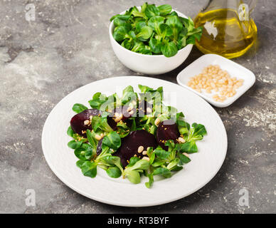Vegetarische Salat von frischen, rohen Gemüse Salat rote Rüben auf eine weiße, runde Platte auf einem grauen Hintergrund. Stockfoto