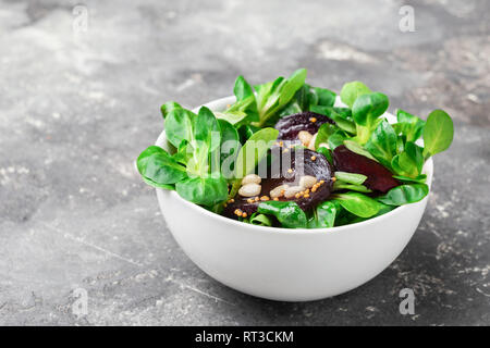 Ein vegetarischer Salat aus frischen Zuckerrüben Gemüse junge Triebe Salatblätter ist in Weiß Schüssel grauer Hintergrund serviert. Stockfoto