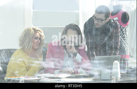 Ansicht von hinter Glas. drei Kollegen diskutieren neue Ideen im Studio Stockfoto