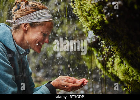 Chile, Patagonien, Vulkan Osorno, Frau erfrischend, mit Wasser von Las Cascadas Wasserfall Stockfoto