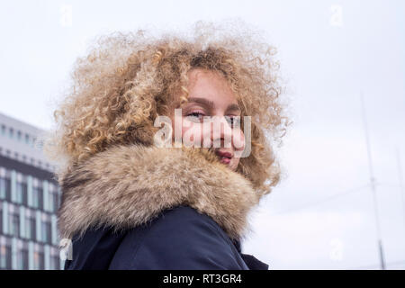 Portrait von lächelnden blonde Frau mit korkenzieherlocken Tragen von Pelz Kragen Stockfoto