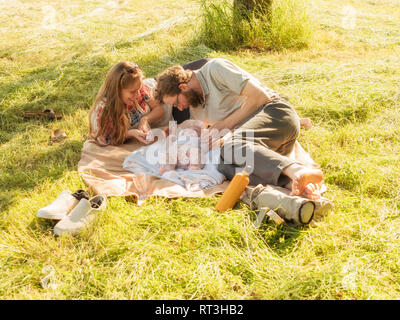 Junges Paar mit Baby Mädchen auf Decken auf einer Wiese Stockfoto