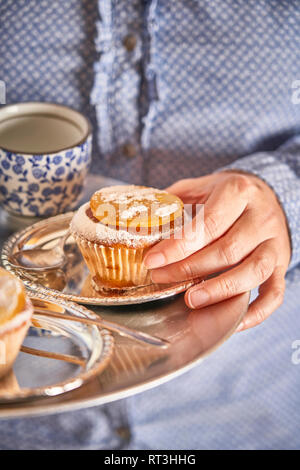 Woman's Hand Muffin mit kandierten Orangen Scheibe auf silbertablett Stockfoto