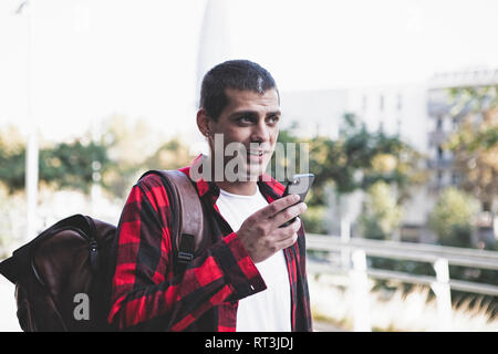 Junger Mann mit Rucksack und Handy unterwegs. Stockfoto