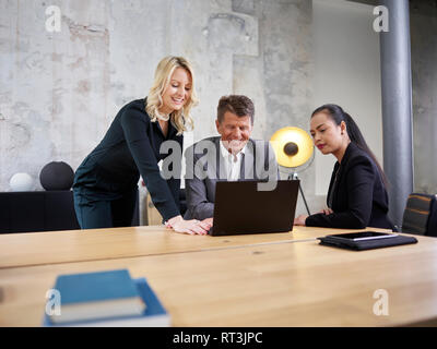 Geschäftsmann und zwei geschäftsfrauen sharing Laptop in modernen Büro Stockfoto