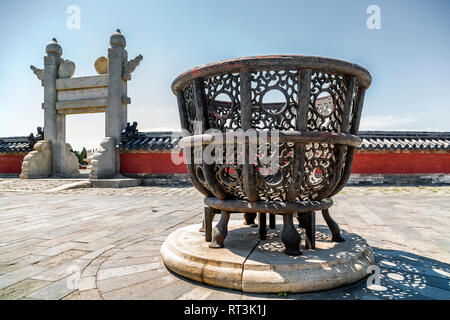 Ein großes reich verzierten Metall Herd oder Feuerstelle ausserhalb Lingxing Tor stehend. Die rote Wand gekrönt mit Blau glasierten Fliesen umgibt die kreisförmige Damm Altar. Stockfoto