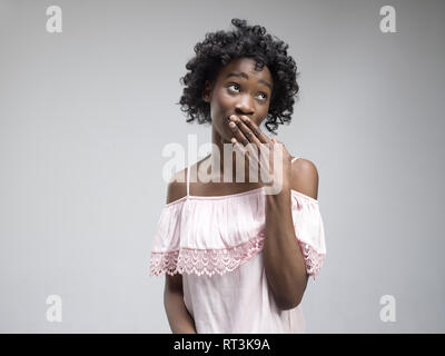 Geheimnis, Klatsch-Konzept. Junge Frau ruft zur Ruhe. Frau am trendigen Grauen studio Hintergrund isoliert. Junge emotionale afrikanische Frau. Menschliche Gefühle, Mimik Konzept. Stockfoto