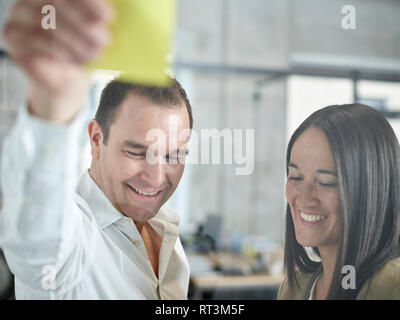 Lächelnd Geschäftsmann und Geschäftsfrau mit haftnotiz im Büro Stockfoto