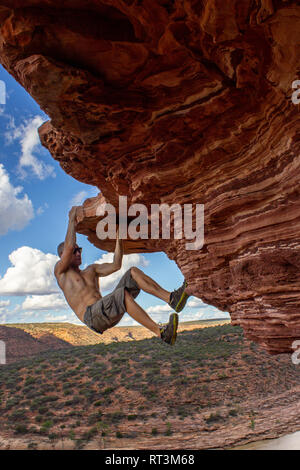 Sorglose Mann ist Klettern auf roten Sandsteinfelsen der Natur des Fensters im Kalbarri National Park Stockfoto