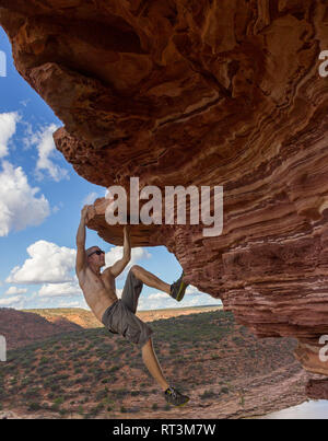 Sorglose Mann ist Klettern auf roten Sandsteinfelsen der Natur des Fensters im Kalbarri National Park Stockfoto