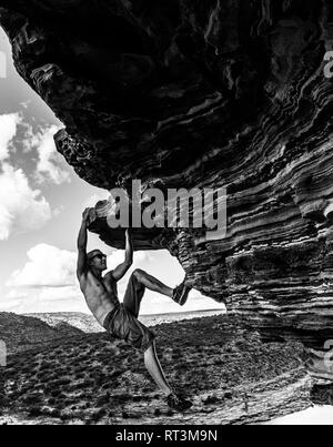 Sorglose Mann ist Klettern auf roten Sandsteinfelsen der Natur des Fensters im Kalbarri National Park Stockfoto