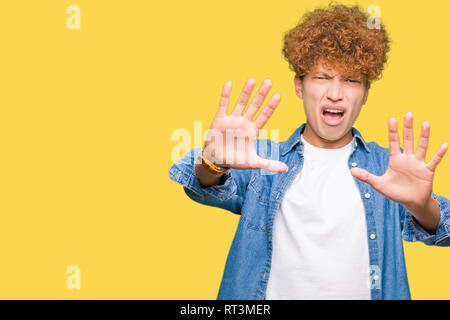 Junger stattlicher Mann mit afro Haar Jeansjacke mit Angst und Furcht Ausdruck stop Geste mit den Händen, Angst, Schreien im Schlag. Panik con Stockfoto