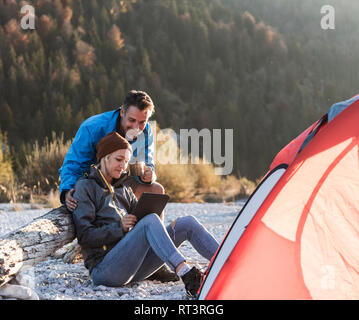 Reifes Paar camping am Flußufer im Abendlicht Stockfoto