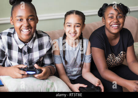 Porträt Lächeln tween girl friends spielen Video Game auf dem Sofa Stockfoto