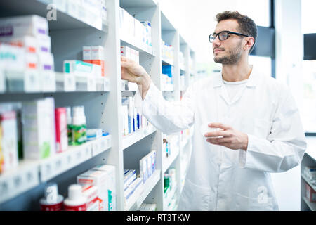 Apotheker, die Medizin von Regal in der Apotheke Stockfoto