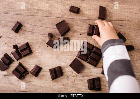 Boy's Hand, denn Stück Schokolade Stockfoto