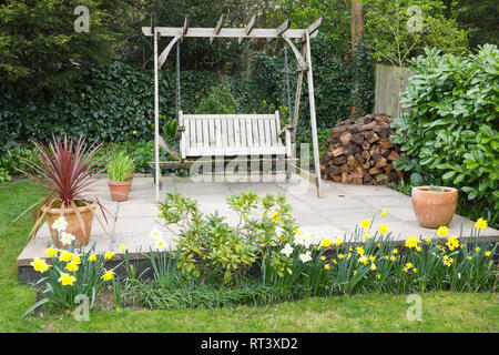 Garten Terrasse im Frühjahr mit Narzissen und ein hölzernes Schwingen Sitzbank Stockfoto