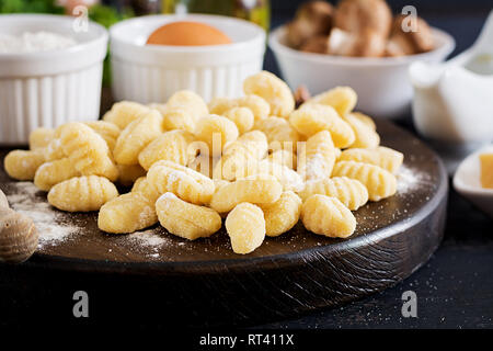 Ungekocht Hausgemachte Gnocchi mit einem Pilz Rahm Sauce und Petersilie in der Schüssel auf einem dunklen Hintergrund. Stockfoto