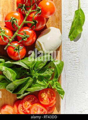 Büffel Mozzarella mit Tomaten, grünen Blätter Basilikum, auf einem urigen Textur Hintergrund Stockfoto