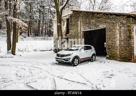 Kia Sportage 2.0 CRDI Awd oder 4x4, Farbe weiß, in der Nähe der verlassenen Garage in einem Wald, bedeckt mit Schnee und Eis. Extreme Bedingungen und temperatu Stockfoto