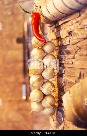 Roter Pfeffer würzig Knoblauch Balken hängen an der Wand Textur Stockfoto
