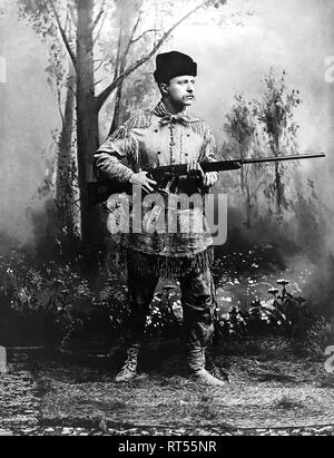 Theodore Roosevelt, mit einem Gewehr beim Tragen eines Hirschfell Jagd Klage im Jahr 1885. Stockfoto