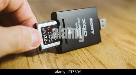 PARIS, Frankreich, 26.MÄRZ 2017: Man fügt Neue XQD Daten Speicherkarte von Sony, Nikon und Sony video foto Produkte für die Speicherung von Inhalten in USB-XQD Card Reader verwendet werden Stockfoto