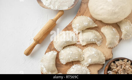 Der Prozess der Herstellung hausgemachte Rohteig Knödel mit Fleisch füllen auf einem Holzbrett. Ukrainische Knödel. Ein traditionelles Gericht. Selektiver Fokus Stockfoto