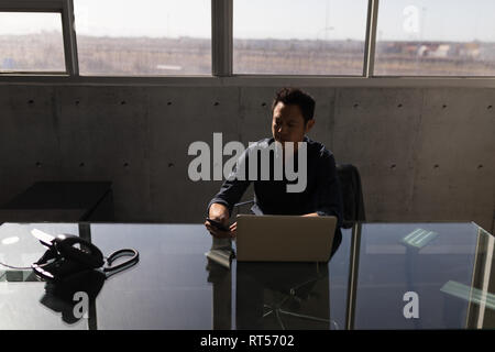 Geschäftsmann mit Handy im Büro Stockfoto