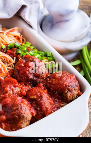 Hausgemachtes Rindfleisch Frikadellen mit Spaghetti in marinara Sauce Auflaufform auf rustikalen Holztisch serviert traditionelle italienische Küche, Nahaufnahme, selec Stockfoto