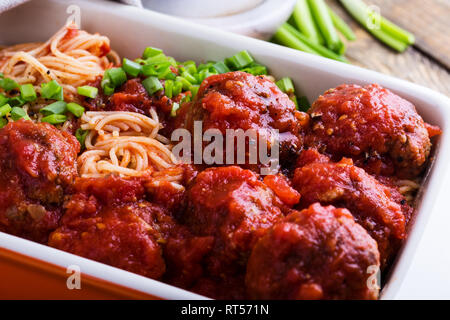 Hausgemachtes Rindfleisch Frikadellen mit Spaghetti in marinara Sauce Auflaufform auf rustikalen Holztisch serviert traditionelle italienische Küche, Nahaufnahme, selec Stockfoto