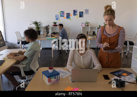 Weibliche Führungskräfte diskutieren über Laptop am Schreibtisch Stockfoto