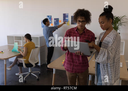 Männliche und weibliche Führungskräfte diskutieren über Laptop im Büro Stockfoto