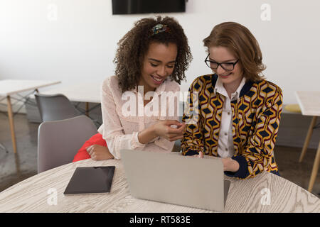 Weibliche Führungskräfte diskutieren über Laptop am Schreibtisch Stockfoto