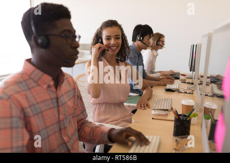 Führungskräfte arbeiten auf dem Computer, während Sie ein Headset im Büro Stockfoto