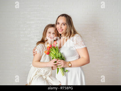 Beauty Portrait von Mutter und Tochter mit Tulpen gegen weiße Wand Stockfoto