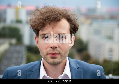 Portrait von Geschäftsmann mit Stoppeln und Lockige braune Haare auf der Dachterrasse am Abend Stockfoto