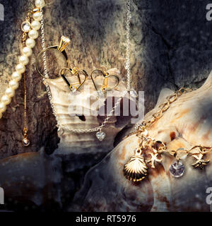 Schatz, Gold Schmuck, Halskette und Ohrringe Ringe auf einer Muschel Hintergrund, closeup Makro Stockfoto