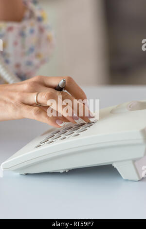 Nahaufnahme der weiblichen Hand Telefon Nummer mit weißen Festnetztelefon. Stockfoto