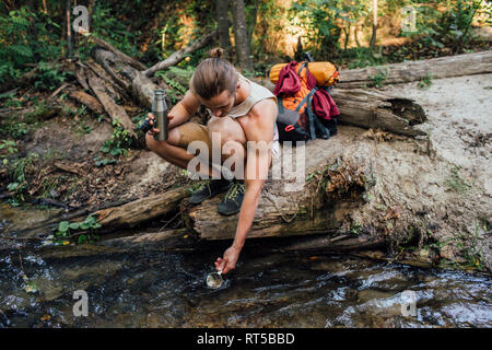 Junge Wanderer scooping frisches Wasser in einem Wald Stockfoto