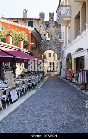 BARDOLINO, Venetien, Italien - 7. AUGUST 2017: Restaurant und Geschäften auf der Straße in Bardolino in der Nähe der San Giovanni Tor. Stockfoto